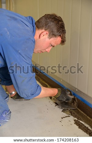 tradesman applying epoxy product to coving around the floor of an industrial building