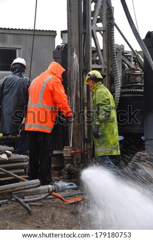 MOANA, NEW ZEALAND, MARCH 18, 2010: Drilling crewmen control a small blowout at the mouth of a well for coal seam  gas near Moana, New Zealand.