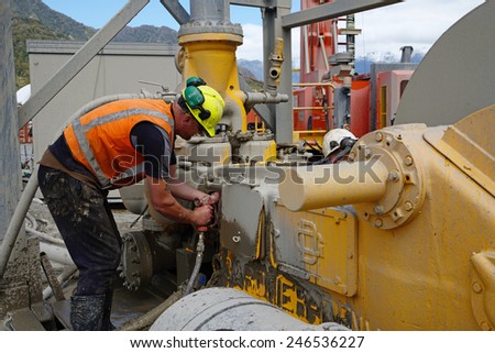 WHATAROA, NEW ZEALAND, DECEMBER 5, 2014: An unidentified driller on the Deep Fault Drilling Project cleans a mud pump during a break while drilling to 1300 metres near Whataroa, New Zealand
