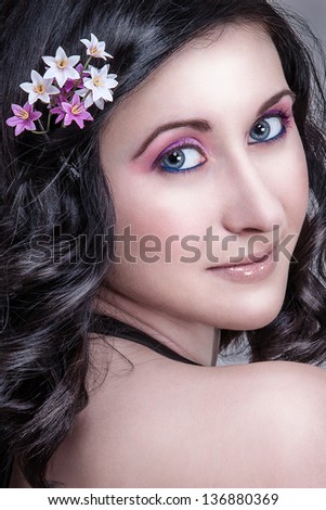 Beautiful girl with flowers in the hair and purple makeup