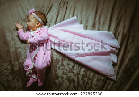 Image of cute little girl in pink suit and cloak indoor. Newborn baby, caucasian child. Super hero in her dreams.
