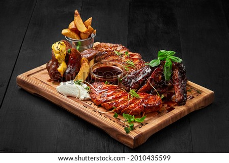 Grilled assorted meat platter with potato wedges and sauces Foto stock © 