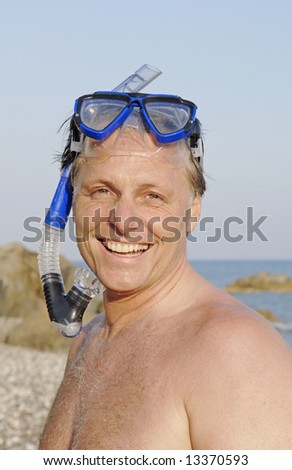 A happy smiling 44 year old man wearing mask and snorkel enjoying his beach holiday.