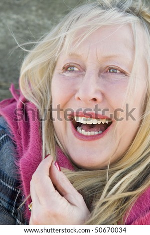 A colour portrait photo of a beautiful older woman in her sixties happy and smiling.
