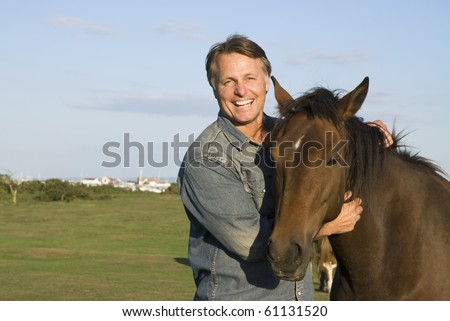 color portrait photo of a hppy smiling forties man petting his horse