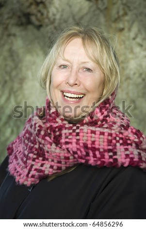 A happy smiling older woman wearing pink scarf