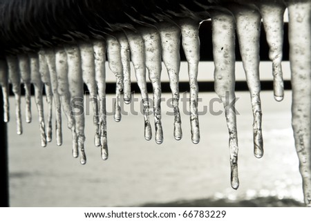 Frozen icicles hanging down from a metal pole.