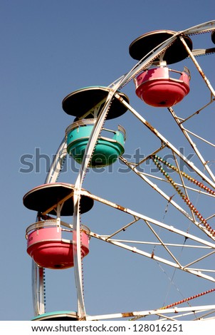 Colorful Ferris wheel spins against a clear blue sky.