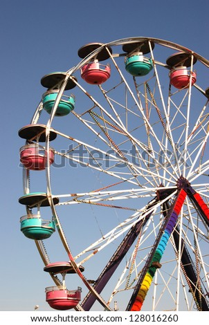 Colorful Ferris wheel spins against a clear blue sky.