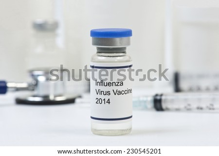2014 influenza vaccine vial with office supplies in background.