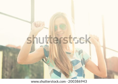 beautiful blond girl in sunglasses standing around the walls with graffiti sunset light