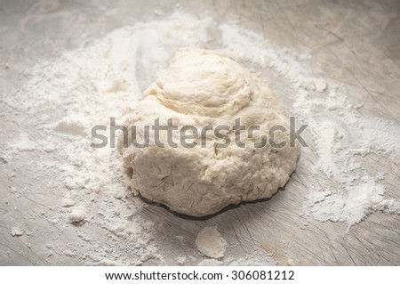 Ball of fresh homemade bread or pizza dough on a scratched kitchen bench, ready for kneading.