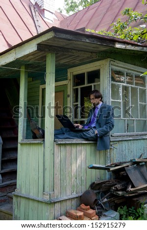 Business man using a laptop with an old village house