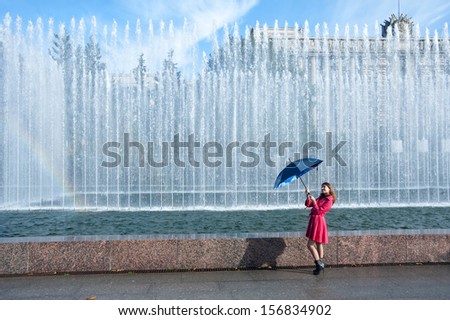 happy young woman in a red raincoat with an umbrella