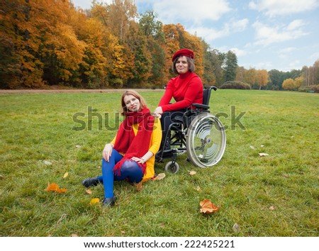disabled with a friend walking in the autumn Park