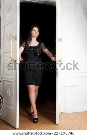 woman in short black dress is at the white door