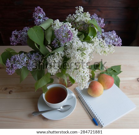 Tea with apples and bouquet of lilac on the table