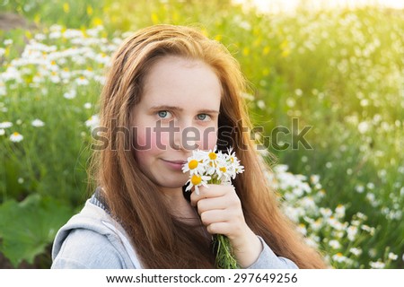 girl with long hair collecting daisies in the field