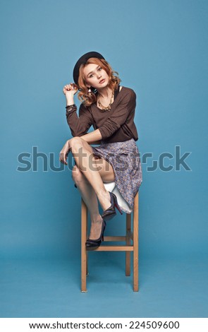 stylish woman sitting on a chair on a blue background