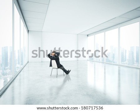 Businessman sitting in empty bright office and look at city