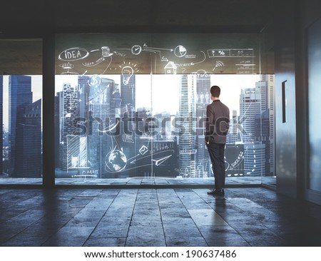 Businessman looking at city through window with drawing business strategy