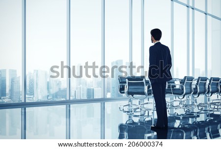 Businessman standing in bright modern office with large windows