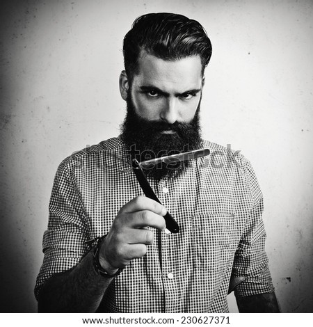 B/w portrait of a handsome bearded man with straight razor