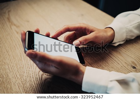 Smartphone holding in female hand on the wood table