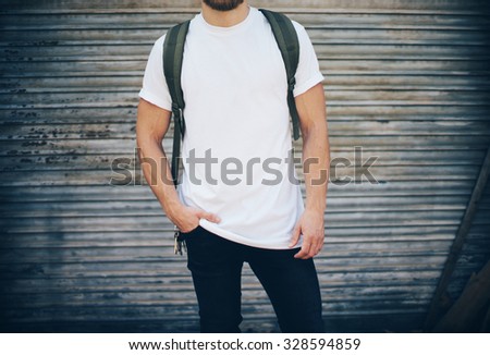 Bearded man wearing white blank t-shirt, blue jeans and green backpack