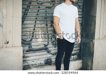 Bearded guy wearing white blank t-shirt and blue jeans, standing on the street