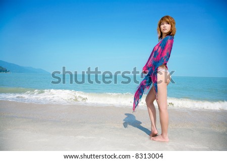 woman stand by the beach with floral scarf wrap around her shoulder
