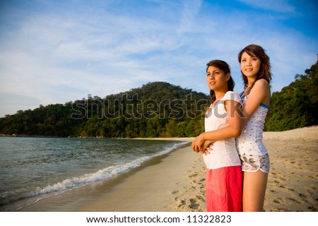 asian best friends hugging each other by the beach enjoying sunset