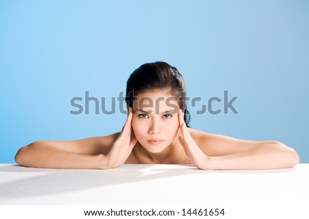 young woman hands rubbing on forehead looks straight on