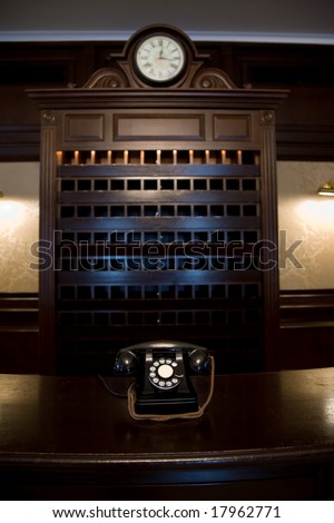 old vintage hotel lobby desk with telephone and clock and key shelf