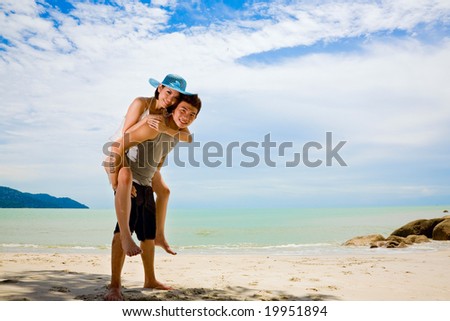 happy loving couple having fun piggyback at the sunny day beach