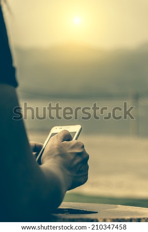Close up of Mobile phone in a woman\'s hand, in sunset