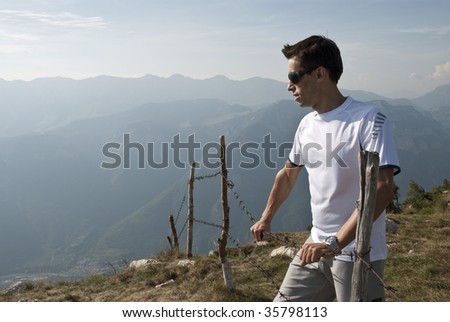 Young man against mountain background in a countryside hiking style scenery.