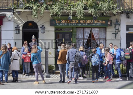 LONDON, UK - APRIL 22: Tourists pose with actor dressed in traditional British police uniform at the entrance of the Sherlock Holmes museum. April 22, 2015 in London.