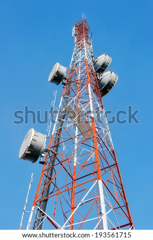 Telecommunication mast with microwave link and TV transmitter antennas on blue sky.