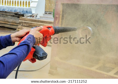 Workers use blowers cleaning a machine in factory.