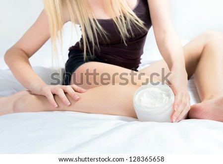 Self caring female applying creme on leg