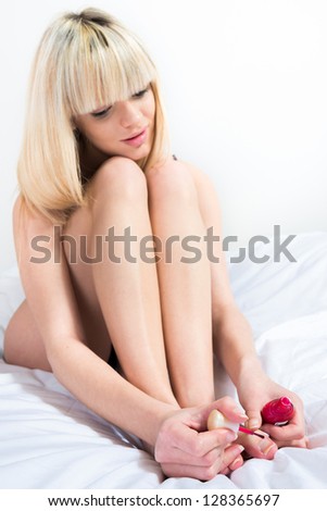 Portrait of pretty woman applying nail lacquer on her feet