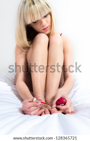 Portrait of cute woman applying nail lacquer on her feet