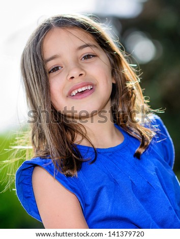 Natural portrait of cute smiling child with greenery in the background