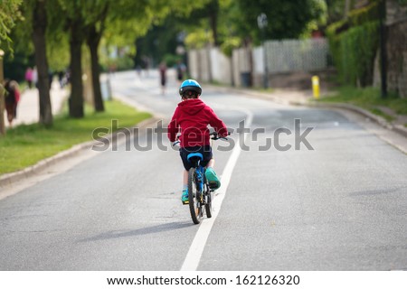 young child doing the bike alone in the middle of the road