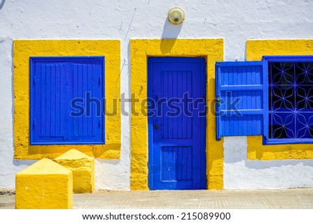 A white wall with an old-fashioned colorful wooden door and two windows on both sides