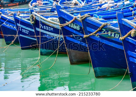 Essaouira - Maroc - 17 August 2013 - Prows of small blue boats lines next to one another and moored at sea port by long roaps