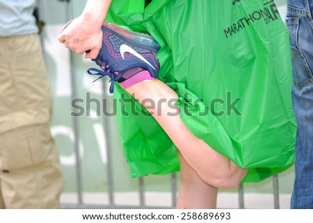 PARIS, FRANCE - APRIL  06 : Woman holding sore leg muscle at Paris International Marathon on April 06, 2014 in Paris, France