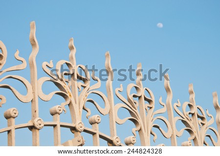 wrought-iron palace fence close-up with moon in the background.