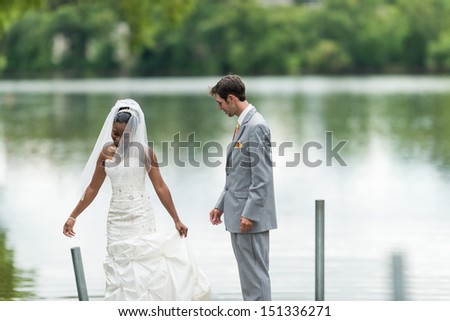 Bride showing off her dress to the groom next to a lake during wedding day